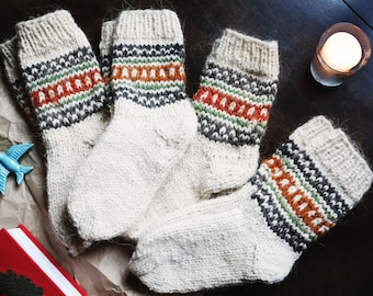 May include: Five pairs of white knitted socks with orange, green, and gray stripes. The socks are folded and arranged on a brown surface.