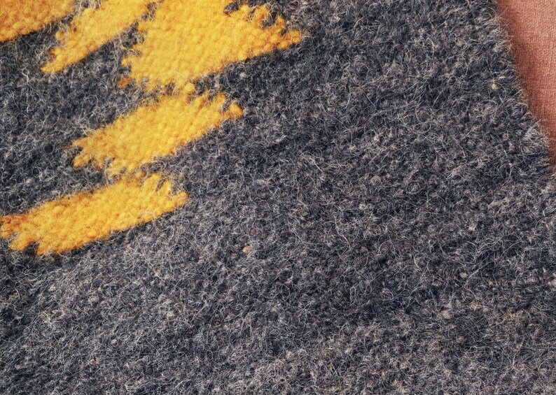 May include: Close-up of a gray fuzzy fabric with a yellow stripe pattern.