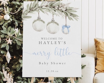 May include: A white sign with a watercolor illustration of Christmas ornaments hanging from a branch. The sign reads "Welcome to Hayley's merry little Baby Shower 11.28.xx".