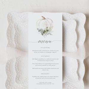 May include: A white pumpkin with green leaves and a menu card with the text "Menu", "Starters", "Entrees", "Dessert", and "Thank you for celebrating with us".