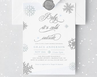 Op de afbeelding: Een witte babyborrel uitnodiging met een bijpassende envelop, verzegeld met een zilveren wasstempel. De uitnodiging bevat de zin "Baby, it's cold outside" in elegant schrift, samen met sneeuwvlok illustraties en evenement details.