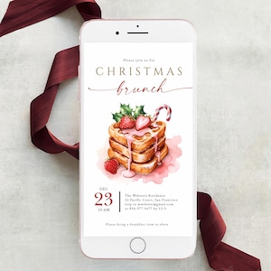 May include: A rose gold smartphone displays a Christmas brunch invitation. The invitation features a watercolor illustration of pancakes with strawberries and a candy cane. A burgundy ribbon is draped around the phone.
