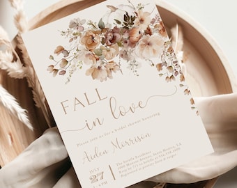 May include: A beige invitation card with floral watercolor design and the words "FALL in love". The card is placed on a wooden tray with a beige cloth and dried plants. The invitation is for a bridal shower.