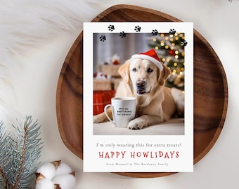 May include: A Christmas card featuring a golden retriever wearing a Santa hat and holding a mug that says "Will do ANYTHING for treats!" The card has a red and white "Happy Howlidays" message and paw prints in the background.