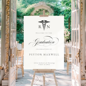 May include: A white welcome sign with a black medical symbol and the text "RN" above the words "Welcome to the Graduation Celebration of Peyton Maxwell UCLA School of Nursing Class of 20xx".