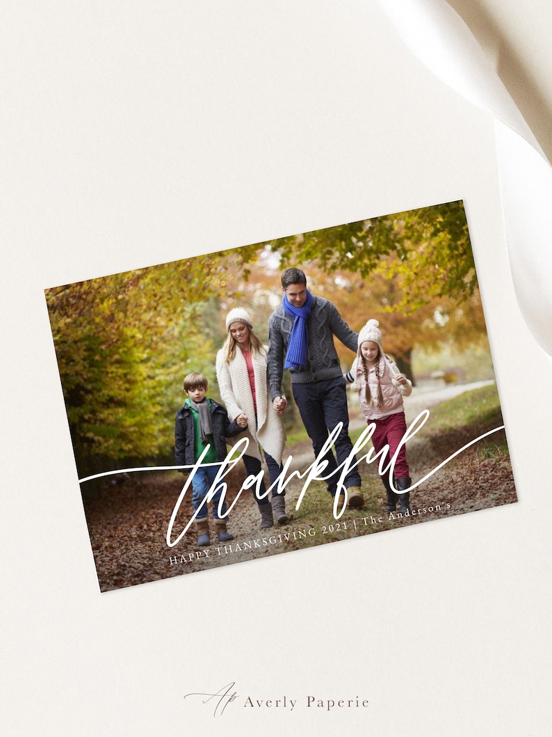 Puede incluir: Una familia de cuatro personas camina por un sendero en un bosque de oto&ntilde;o. Los padres van de la mano con sus dos hijos. El texto "thankful" est&aacute; escrito en cursiva blanca sobre la imagen. El texto "Happy Thanksgiving 2021 | The Anderson's" est&aacute; escrito debajo del texto en cursiva.