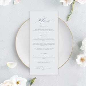 May include: A light blue menu card with a handwritten 'Menu' title. The menu lists starters, entrees, and desserts. The text includes 'Mixed greens with candied pecans, strawberries, goat cheese, and shallots in champagne vinaigrette.' and 'Filet Mignon medallions in a sinfandel reduction with roasted potatoes and green beans.'
