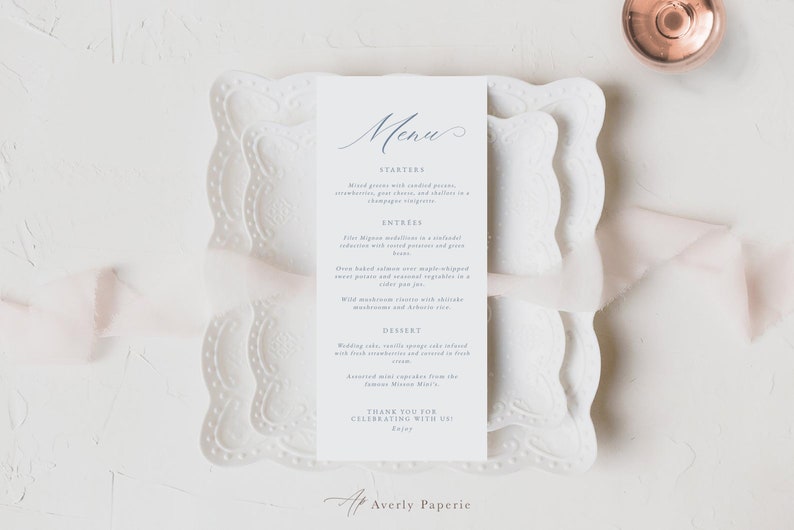 May include: A white wedding menu card with blue calligraphy text. The menu includes starters, entrees, dessert, and a thank you message. The card is on a white lace doily.
