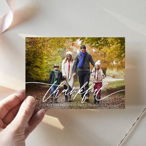 Puede incluir: Una tarjeta de Acci&oacute;n de Gracias con una familia de cuatro personas caminando por un bosque de oto&ntilde;o. La tarjeta tiene la palabra "thankful" escrita en cursiva blanca y el texto "Happy Thanksgiving 2021 | The Anderson's".