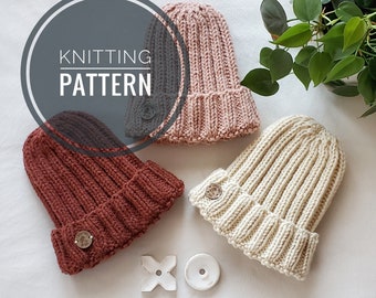 May include: Three knitted hats in different colors: beige, pink, and burgundy. Each hat has a button on the side. The hats are arranged on a white surface with a small white cross and a white button.