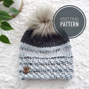 Może przedstawiać: Szary i biały wełniany beret z pomponem z imitacji futra. Beret ma biały pasek z wzorem w różowe i szare plamki. Beret ma drewniany guzik z logo drzewa. Tekst "Knitting Pattern" jest napisany w kółku na obrazku.
