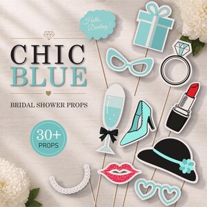 Op de afbeelding: Een verzameling "Chic Blue" rekwisieten voor een bruidsdouche. De rekwisieten omvatten een geschenkdoos, ring, lippenstift, hoge hak, hoed, bril, lippen en een champagneglas. De rekwisieten zijn in tinten blauw, zwart en wit.