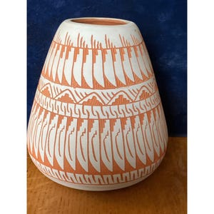 Jarrón de cerámica navajo hecho a mano, firmado por Laura, con diseño geométrico en rojo y blanco.