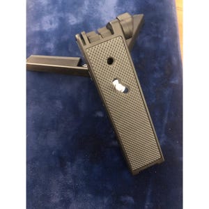 Pode incluir: Uma placa de liberação rápida preta para tripé de câmera com superfície texturizada e parafuso de montagem. A placa é retangular com punho emborrachado e pequena alavanca de travamento branca. Para equipamentos de fotografia.