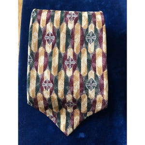 Puede incluir: Una corbata de seda estampada con un diseño geométrico en tonos dorados, burdeos y verdes.
