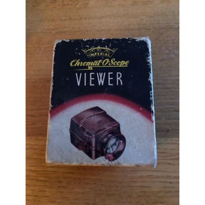 May include: Vintage "Chromat O'Scope VIEWER" in its original box. The box is black with gold lettering and a graphic of the viewer. The viewer is a dark brown color. The box has a crown design at the top.