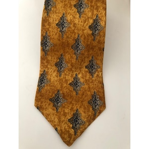 Puede incluir: Una corbata de seda dorada con un patrón geométrico azul y blanco.