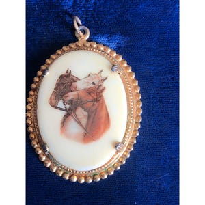 Colgante ovalado vintage en tono dorado con ilustración de caballo y diseño de borde festoneado.