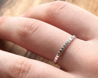 Puede incluir: Un anillo de plata con una fila de pequeñas cuentas redondas texturizadas.