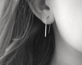May include: A pair of simple silver hoop earrings. The earrings are thin and have a slightly hammered texture.