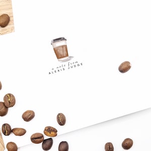 May include: A white card with a brown coffee cup illustration and the text "a note from ALEXIS JUDGE". Coffee beans are scattered around the card.