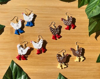 May include: Six pairs of handmade polymer clay earrings featuring chickens wearing boots. The chickens are white, brown with white polka dots, and brown with white spots. The boots are red, blue, and yellow.