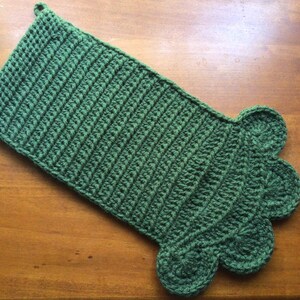 May include: A green crocheted stocking with a scalloped edge. The stocking has a loop at the top for hanging.