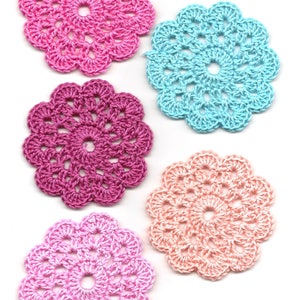 Puede incluir: Cinco doilies de ganchillo en varios tonos de rosa, melocotón y azul. Los doilies son circulares y presentan un diseño delicado y de encaje.