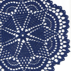 May include: A blue crocheted doily with a circular design. The doily has a delicate, intricate pattern with a central flower motif.