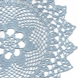 Puede incluir: Un encaje de ganchillo de color azul claro con un delicado patrón floral.