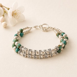 May include: A double-strand bracelet featuring turquoise and silver beads. The bracelet includes silver letter beads spelling "LILAH" and "WESLEY". The bracelet is connected with a silver clasp.