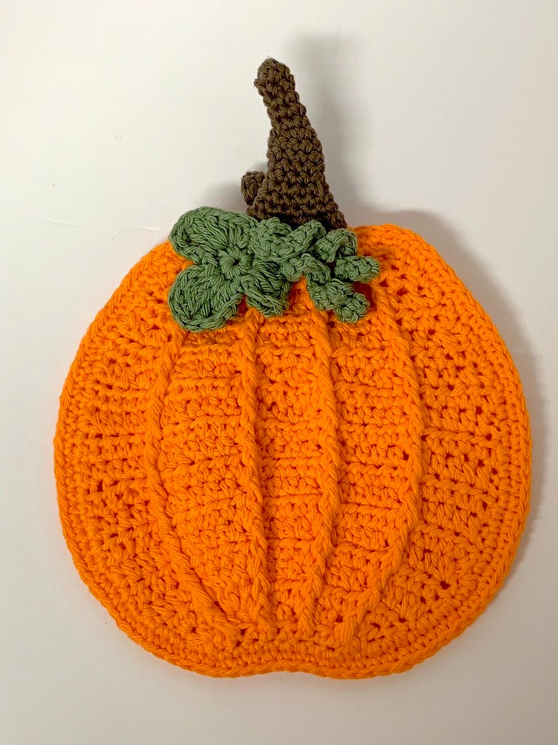 May include: A crocheted orange pumpkin with a brown stem and green leaves.