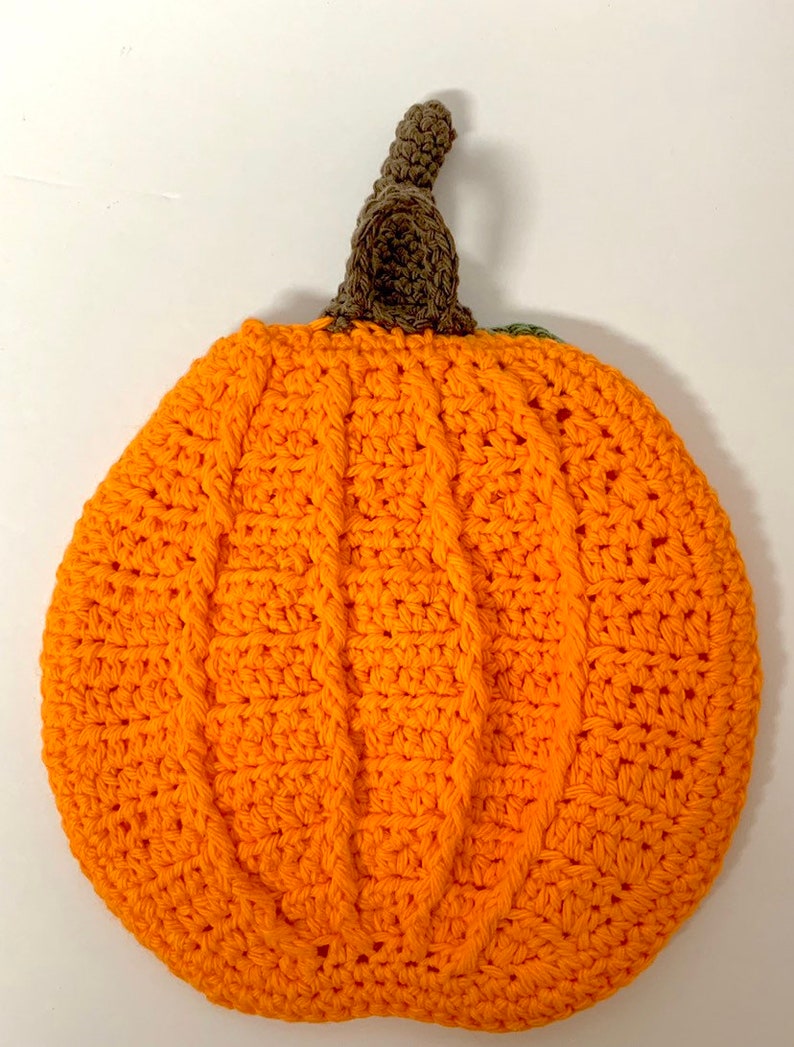 May include: A crocheted pumpkin with a brown stem and orange body. The pumpkin is made with a cable stitch pattern.