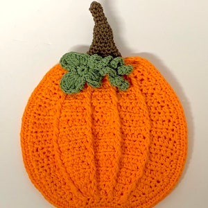 May include: A crocheted orange pumpkin with a brown stem and green leaves.