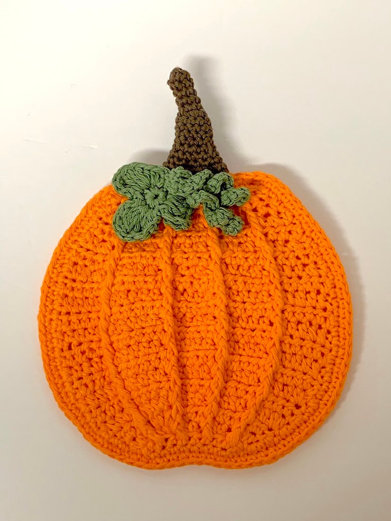 May include: A crocheted orange pumpkin with a brown stem and green leaves.
