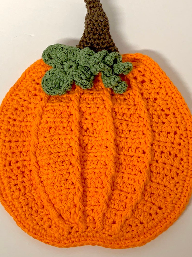 May include: A crocheted orange pumpkin with a green crocheted stem and leaves.