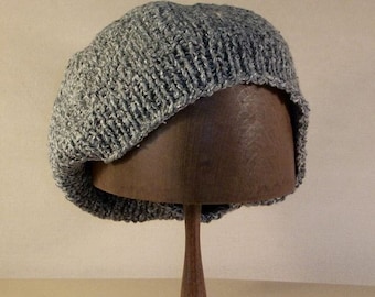 May include: A gray knitted beanie with a slouchy fit, displayed on a wooden hat stand.