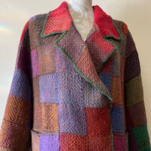 May include: A long, multi-colored knitted cardigan with a patchwork design. The cardigan has a large collar and a double-breasted closure.