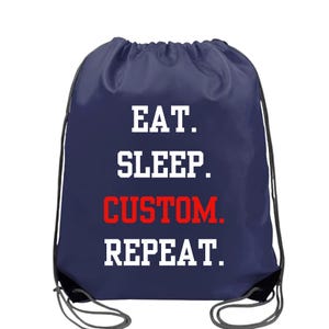 May include: Navy blue drawstring backpack with white and red text. The text reads "EAT. SLEEP. CUSTOM. REPEAT." The bag has black drawstrings and a white background. This bag is suitable for carrying gym clothes, books, or other personal items.