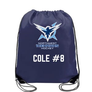 May include: A navy blue drawstring bag featuring a white and light blue graphic of a hawk logo above the text NORTHWEST ICEHAWKS HOCKEY. Below the logo, the name COLE and the number #8 are printed in bold white capital letters.