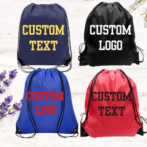 May include: Four drawstring bags in navy blue, black, royal blue, and red. The navy bag features yellow text reading CUSTOM TEXT. The black bag has white text reading CUSTOM LOGO. The royal blue bag has red text reading CUSTOM LOGO. The red bag has black text reading CUSTOM TEXT.