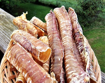 May include: A wicker basket filled with a variety of dried, rolled, and textured dog chews. The chews are a light brown color and have a natural, meaty appearance.