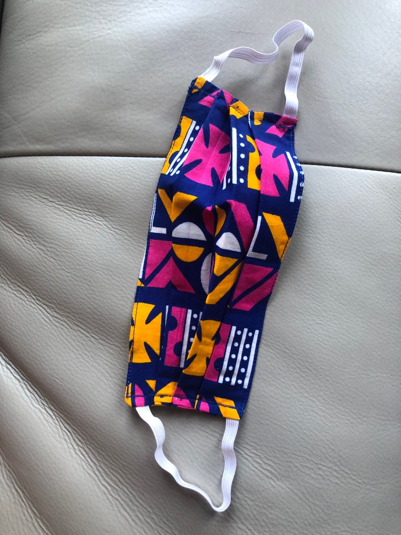 May include: A blue, pink, and yellow patterned face mask with white elastic straps.