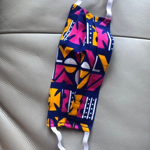 May include: A blue, pink, and yellow patterned face mask with white elastic straps.