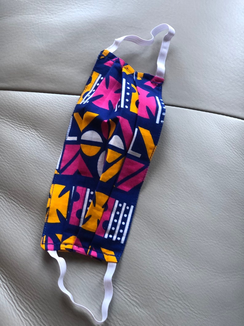 May include: A blue, pink, and yellow patterned face mask with white elastic straps.
