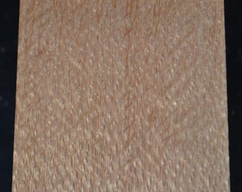 May include: A close-up of a piece of wood veneer with a light brown color and a unique, textured grain pattern.