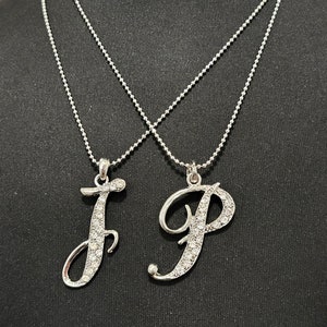 May include: Two silver necklaces with crystal-encrusted letter pendants, one with the letter 'J' and the other with the letter 'P'.