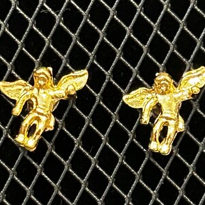 Pode incluir: Um par de brincos de asa de anjo de ouro. As asas s&atilde;o detalhadas e t&ecirc;m um aspeto tridimensional.
