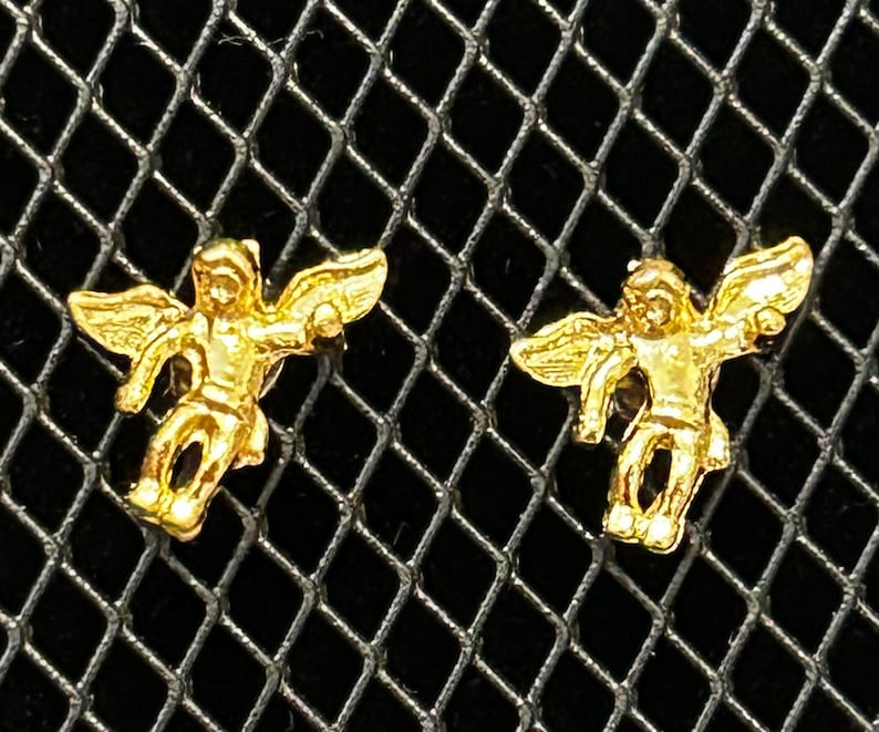 Pode incluir: Um par de brincos de asa de anjo de ouro. As asas s&atilde;o detalhadas e t&ecirc;m um aspeto tridimensional.