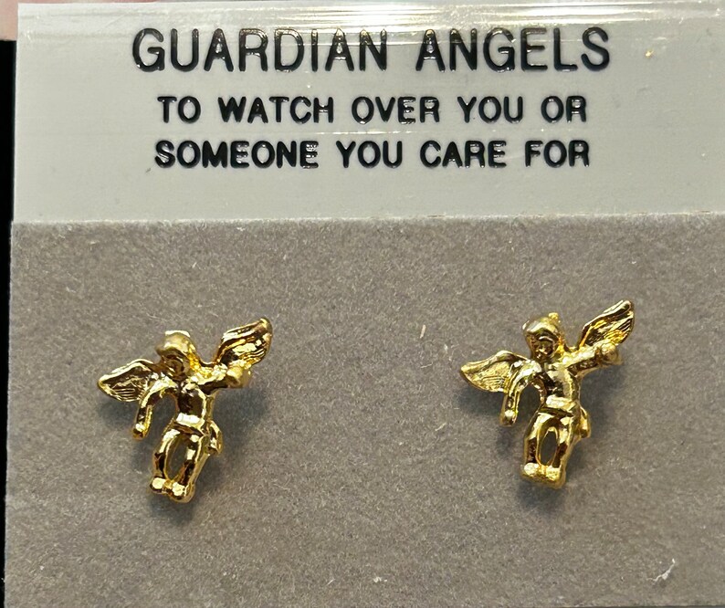Pode incluir: Um par de brincos de anjo da guarda em tom dourado. Os brincos apresentam um pequeno anjo com as asas abertas. O cart&atilde;o diz "Guardian Angels To Watch Over You Or Someone You Care For".